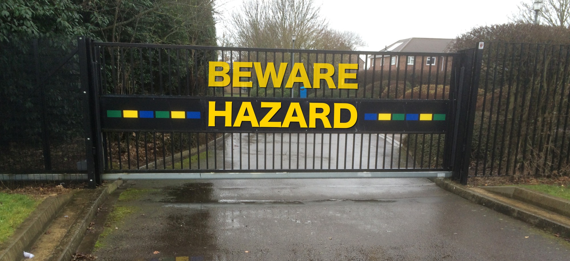 Beware Hazard sign superimposed on automated gate